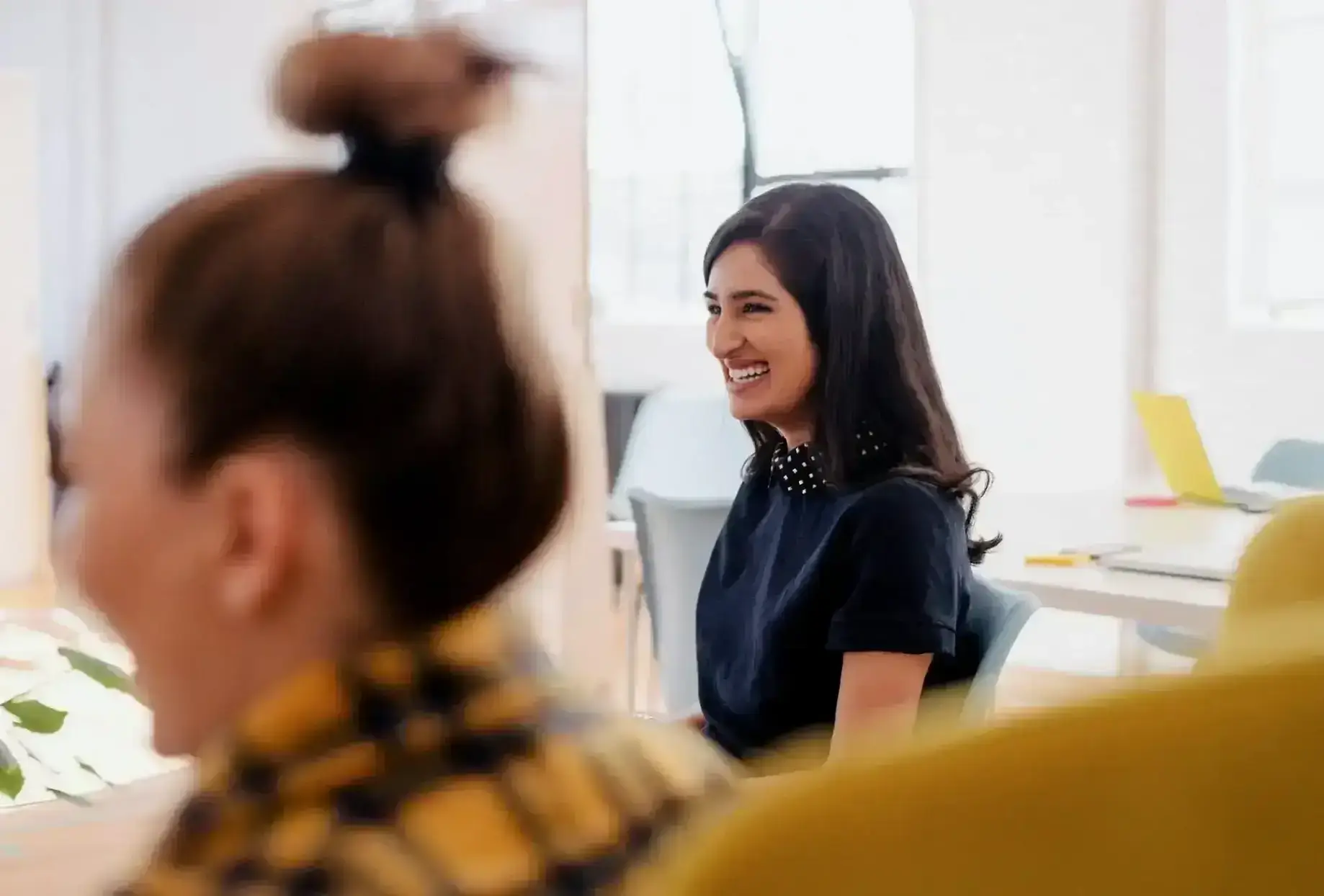 A lady sitting on a sofa smiling while chatting 